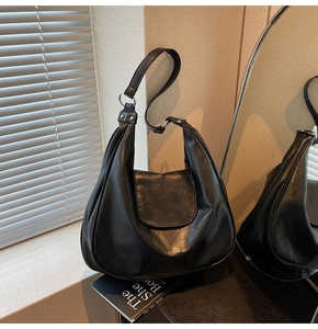Detail of black hobo bag with pleated texture, silver rings, and rivet decorations