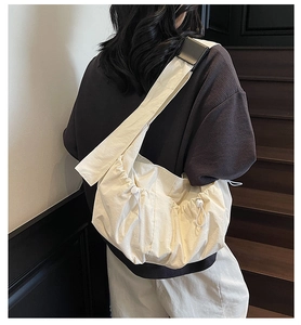 Detailed view of cream pleated crossbody bag with drawstring side knots and wide strap