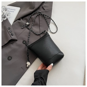 Détail du mini sac seau noir grainé avec chaîne argentée et pendentif en cœur