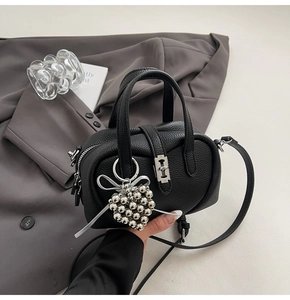 Détail du mini sac Boston noir en cuir grainé avec charm coeur et garniture argentée