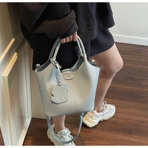 Close-up of light blue lychee pattern bucket bag with dog charm and MOINBA logo