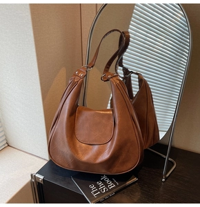 Detail of vintage brown leather shoulder bag featuring side pleats and silver metal hardware