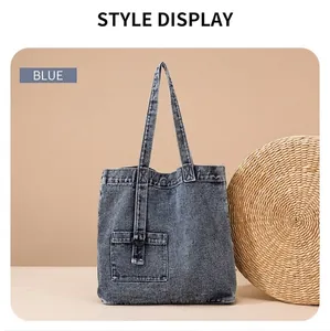 Blue denim tote bag detail featuring a decorative front pocket with metal buckle ring