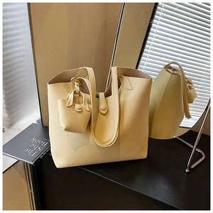 Detail of large cream leather tote bag with pebble grain texture and coin purse charm