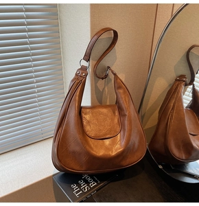 Detail of vintage brown PU leather hobo bag showing soft texture and metal buckle