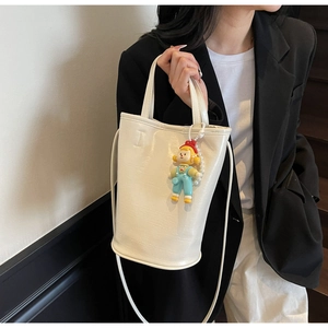 Detail of white leather bucket bag with FASHION lettering and a small cartoon charm