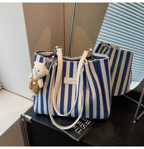 Détail du cabas en toile rayée bleue et blanche avec anses en cuir et petit ours