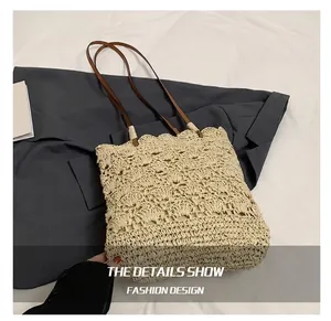 Close-up of woven straw shoulder bag with beige scallop patterns and brown leather straps