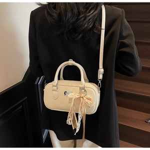Dettaglio borsa boston beige intrecciata con fiocco in pizzo e tracolla regolabile
