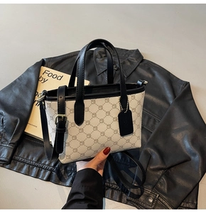 Détail d'un sac seau à motifs avec des lanières en cuir noir et accessoire pendentif