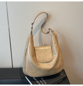 Detailed view of the pleated texture and silver hardware on a beige dumpling shoulder bag