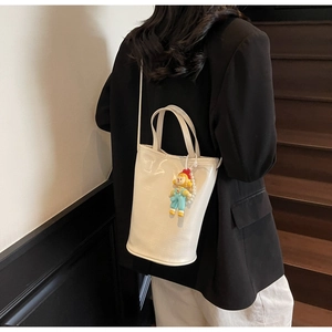 Detail of cream glossy bucket bag with fashion lettering and cute cartoon doll charm