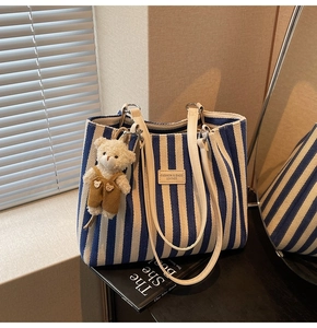 Détail du grand sac cabas rayé bleu avec bandoulière en cuir blanc et charme d'ours