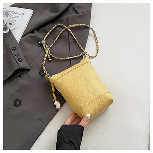 Détail d'un sac seau jaune gingembre avec texture litchi et bandoulière argent