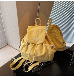 Dettaglio di uno zaino da viaggio in nylon giallo con coulisse e patta alla moda