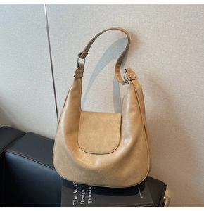 Detail of khaki crescent shoulder bag featuring premium leather pleats and silver metal hardware
