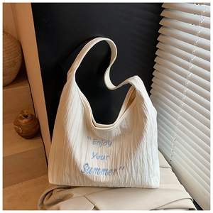 Gros plan du sac cabas beige avec broderie Enjoy Your Summer bleue et texture plissée