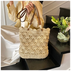 Detail of hand-woven bucket bag featuring a scalloped edge and brown leather handles