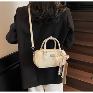 Borsa Boston intrecciata bianco crema con fiocco in pizzo e tracolla su modella