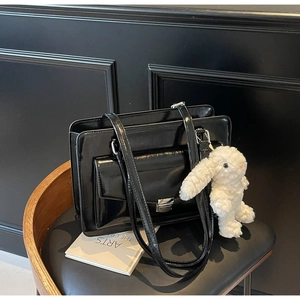 Détail du sac cabas en cuir verni noir avec fermoir argenté et breloque lapin