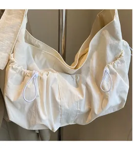Close-up of white dumpling bag showing textured fabric and drawstring pleats details