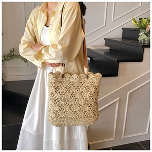 Detail of hand-woven straw bucket bag featuring scalloped crochet patterns and leather straps