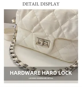 Detail of silver twist lock and quilted texture on a white crossbody chain bag