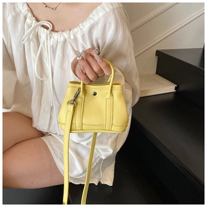 Detail of yellow pebbled leather mini bucket bag with silver hardware and shoulder strap