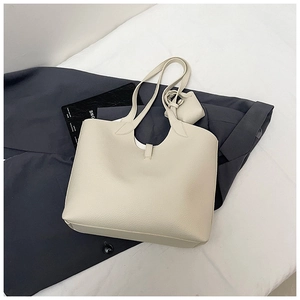 Detail of cream tote bag with lychee texture and matching pouch on a dark blazer