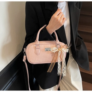Dettaglio della borsa Boston intrecciata rosa chiaro con grande fiocco in pizzo
