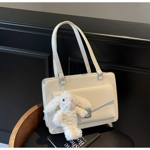 Gros plan d'un sac messager en cuir brillant blanc avec boucle et breloque lapin en peluche