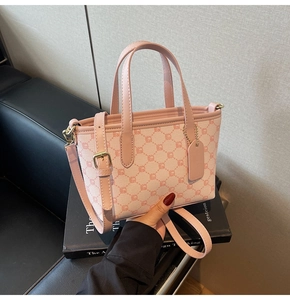 Gros plan d'un mini cabas rose à monogramme avec finitions en cuir sur canapé noir