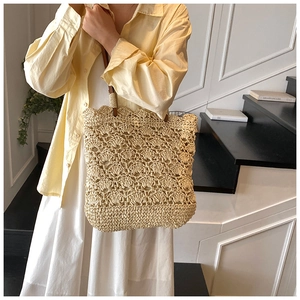 Detail of hollow crochet straw tote bag with fan pattern and brown leather straps