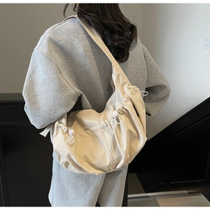 Detail view of cream crescent crossbody bag with drawstring pleats on the shoulder