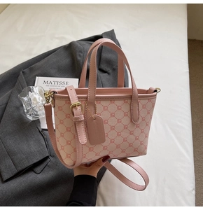 Détail d'un sac seau rose et beige avec motifs géométriques et finitions dorées