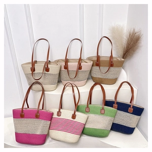 Borse tote in paglia intrecciata colorata con manici in pelle su supporti bianchi