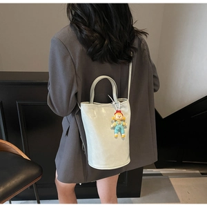 Detail of mint green bucket bag with leather texture and cute cartoon doll pendant