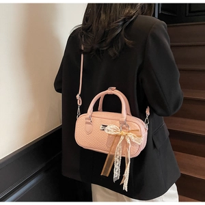 Dettaglio della borsa Boston rosa intrecciata con fiocco in pizzo indossata a tracolla