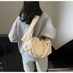 Beige large capacity drawstring nylon hobo bag shown on model in a minimalist setting
