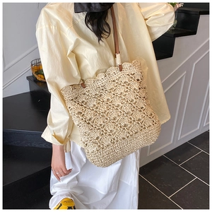 Detail of hand-woven straw tote bag with scalloped edges and slim brown straps