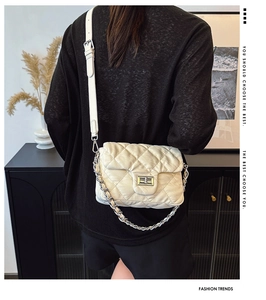Close-up of beige quilted crossbody bag with silver chain strap and metal turn-lock