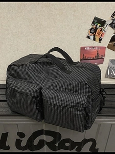 Grand sac de voyage à carreaux noir et blanc avec poches avant sur un banc