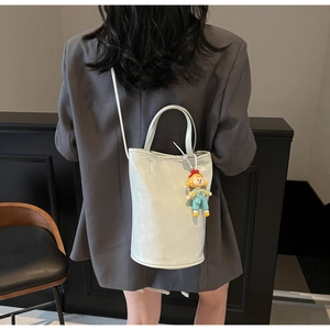 Model view of a mint green bucket bag with doll charm and textured PU leather