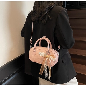 Dettaglio borsa rosa intrecciata con fiocco in pizzo e placchetta in metallo