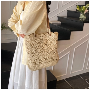 Macro detail of hand-woven straw tote bag with delicate crochet shell patterns and leather strap