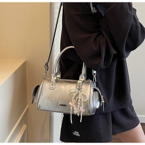 Detail of silver metallic Boston bag with pearl bow charm and detachable long strap