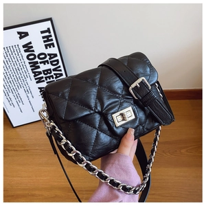 Detail of black quilted crossbody bag with silver twist lock and metal chain strap