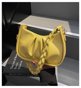 Close-up of bright yellow litchi grain shoulder bag with pleated texture and woven handle