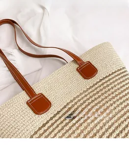 Dettaglio della borsa tote in paglia beige con spalline in pelle marrone e cuciture bianche
