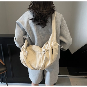 Detail view of cream canvas dumpling bag showing drawstring and large side pocket